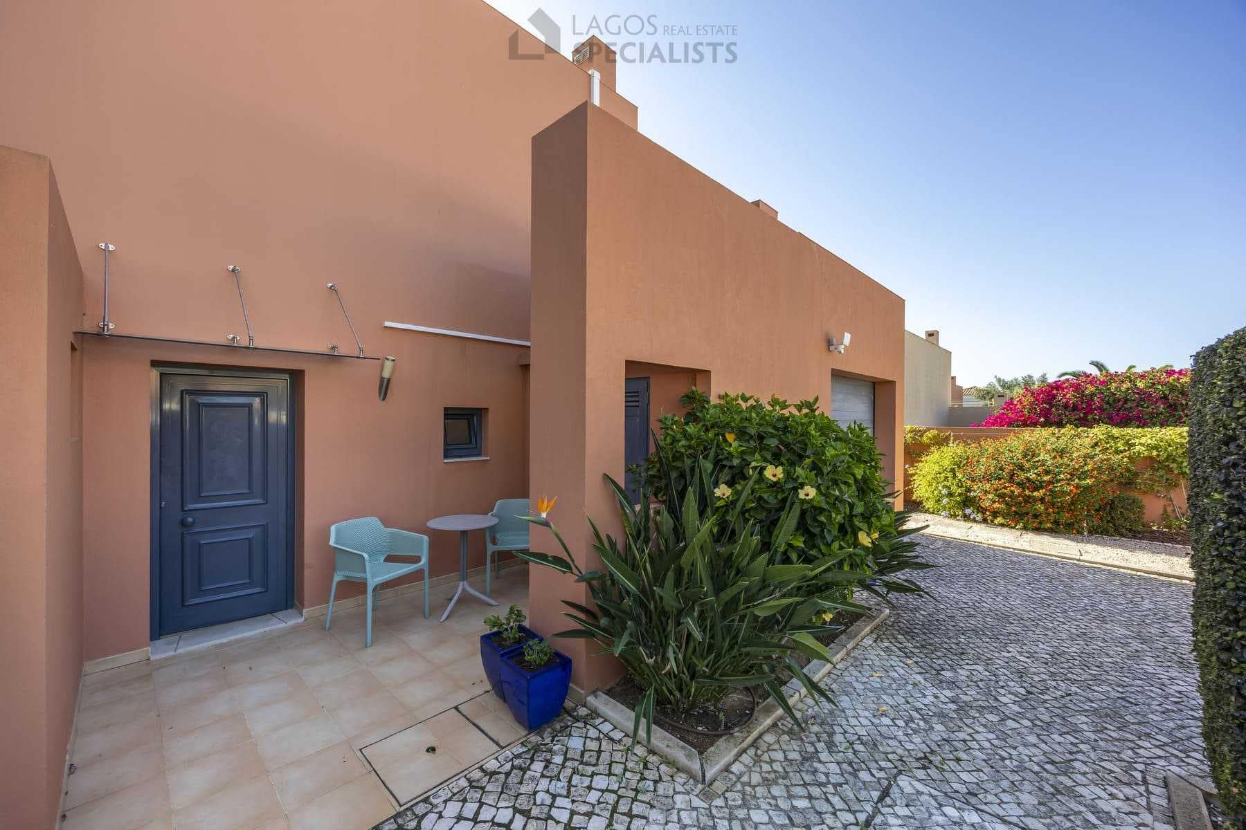 Villa entrance and driveway with garage, cobblestone path and garden