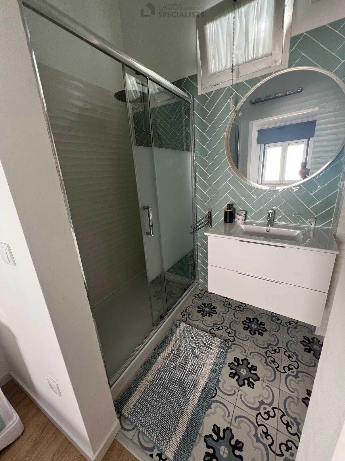 Modern bathroom with walk-in shower and patterned tiles – renovated house in Lagos
