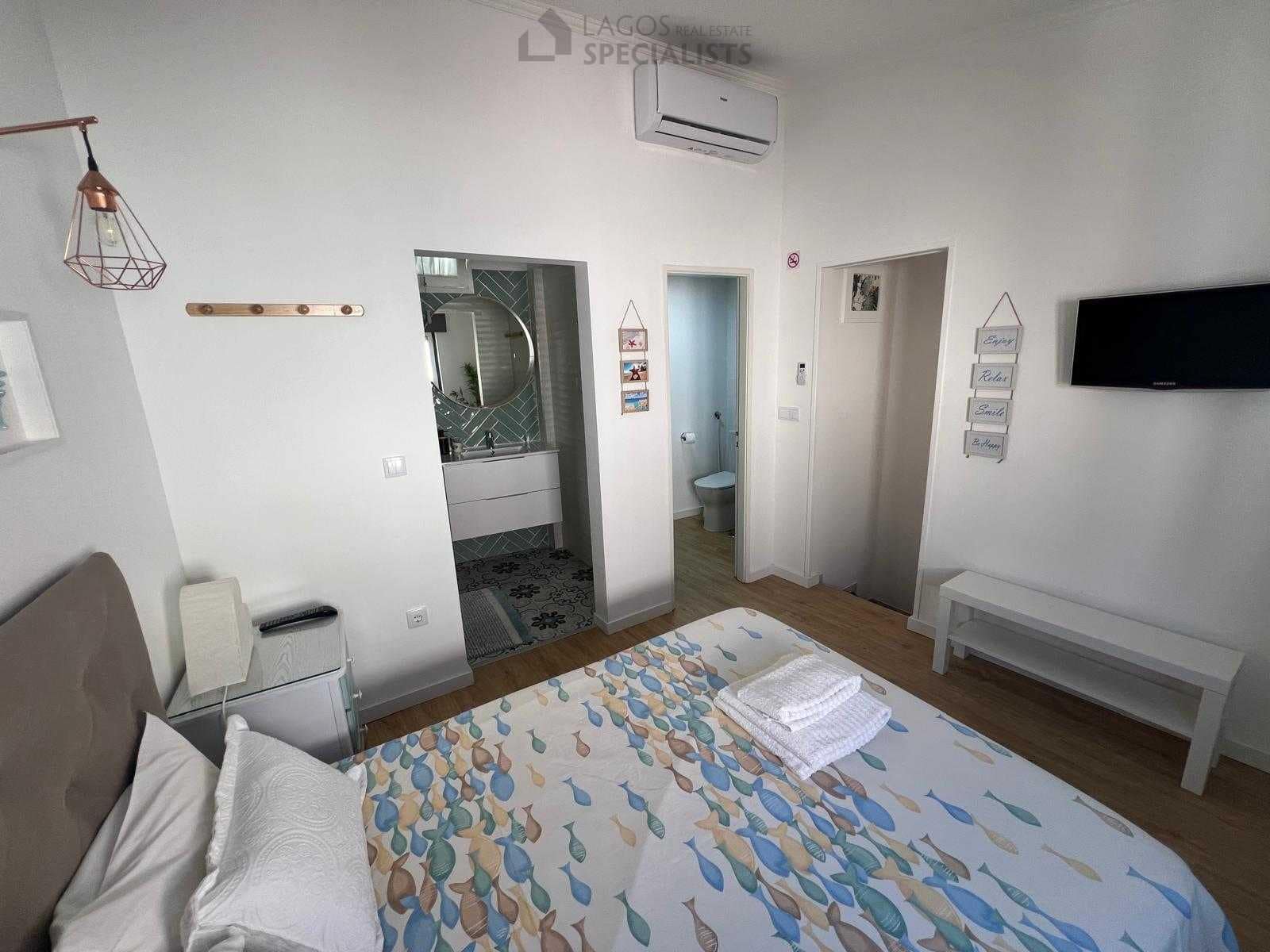 Master bedroom with built-in closets, TV and large windows – renovated 1-bed house in Lagos